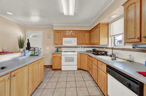 Kitchen featuring sink, crown molding, light tile patterned floors, white appliances, and decorative backsplash