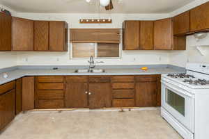 Kitchen with ceiling fan, white range with gas cooktop, and sink