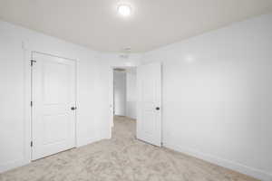 Unfurnished bedroom featuring light carpet, visible vents, and baseboards