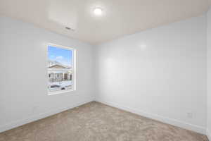 Unfurnished room with baseboards, visible vents, and light colored carpet