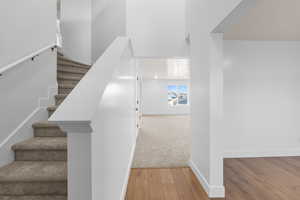 Staircase with a towering ceiling, baseboards, and wood finished floors