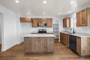 Kitchen featuring appliances with stainless steel finishes, light countertops, a sink, and a kitchen island