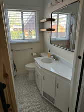 Bathroom featuring vanity, toilet, tile patterned flooring, and a wealth of natural light