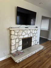 Room details with a stone fireplace and hardwood / wood-style flooring