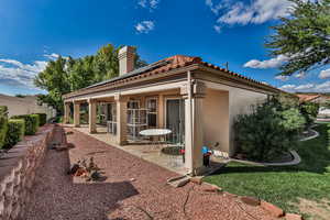 Rear view of property with solar panels and a patio area