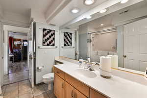 Bathroom featuring vanity, walk in shower, toilet, tile patterned floors, and a textured ceiling