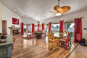 Dining area featuring ceiling fan, vaulted ceiling, a textured ceiling, and light wood-type flooring