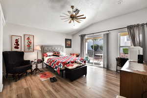 Bedroom with ceiling fan, lofted ceiling, access to exterior, and light hardwood / wood-style floors