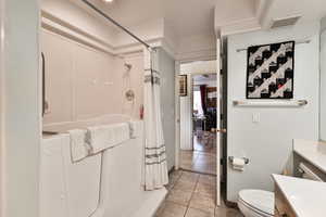 Full bathroom featuring shower / bath combination with curtain, vanity, tile patterned floors, and toilet