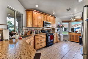 Kitchen with sink, decorative backsplash, light tile patterned floors, stainless steel appliances, and light stone countertops