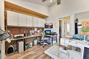 Home office featuring a workshop area, ceiling fan, and light hardwood / wood-style flooring