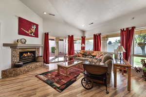 Living room featuring vaulted ceiling, hardwood / wood-style floors, and a textured ceiling