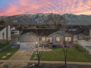 View of front of house featuring a mountain view, a garage, and a lawn