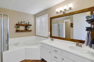 Bathroom with hardwood / wood-style flooring, vanity, and separate shower and tub