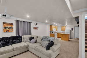 Living room with light colored carpet, ornamental molding, and a textured ceiling