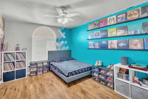 Bedroom with hardwood / wood-style flooring, ceiling fan, and a textured ceiling