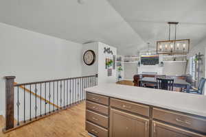 Kitchen featuring hanging light fixtures, lofted ceiling, ceiling fan with notable chandelier, and light hardwood / wood-style flooring