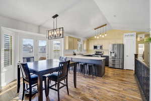 Dining area with lofted ceiling, sink, light hardwood / wood-style flooring, and a chandelier