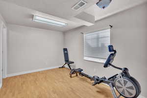 Workout room with a textured ceiling and light wood-type flooring