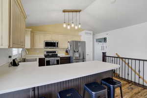 Kitchen featuring decorative light fixtures, sink, a breakfast bar area, kitchen peninsula, and stainless steel appliances