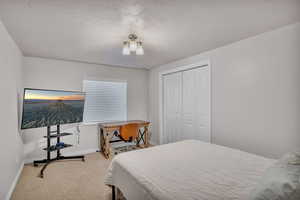 Carpeted bedroom with a closet and a textured ceiling