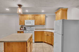 Kitchen with decorative light fixtures, sink, ornamental molding, white appliances, and a textured ceiling