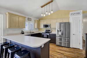 Kitchen with pendant lighting, appliances with stainless steel finishes, a kitchen bar, and kitchen peninsula