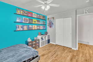 Bedroom featuring hardwood / wood-style flooring, a textured ceiling, a closet, and ceiling fan