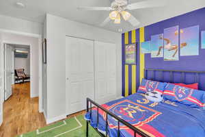 Bedroom featuring ceiling fan, wood-type flooring, and a closet