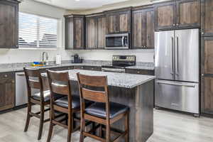 Kitchen featuring quartz countertops, stainless steel appliances, beautiful upgraded cabinets, with a center island