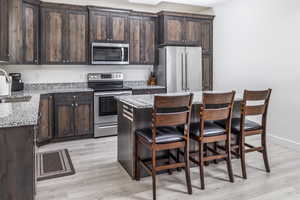 Kitchen featuring quartz countertops, stainless steel appliances, beautiful upgraded cabinets, with a center island