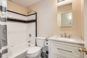 Full bathroom featuring vanity, shower / bath combination with curtain, and toilet