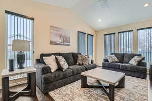 Living room featuring ceiling fan, hardwood / wood-style flooring, vaulted ceiling, and a wealth of natural light