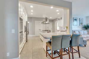 Kitchen with island range hood, sink, white cabinets, kitchen peninsula, and stainless steel appliances