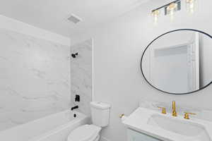 Full bathroom with tiled shower / bath combo, vanity, a textured ceiling, and toilet