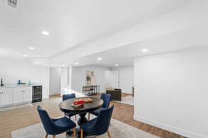 Dining room featuring bar, beverage cooler, and light wood-type flooring