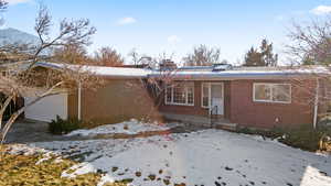 Snow covered rear of property with a garage