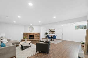 Living room with a stone fireplace and light wood-type flooring