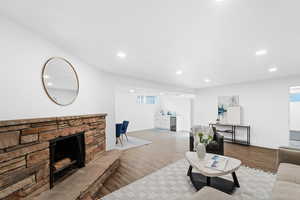 Living room with a stone fireplace, sink, and light hardwood / wood-style flooring