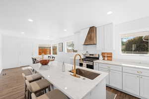 Kitchen with white cabinetry, a center island, custom range hood, and stainless steel gas stove