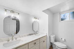 Bathroom with vanity, a textured ceiling, and toilet