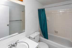 Full bathroom with vanity, shower / bath combination with curtain, and toilet