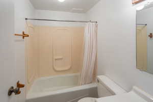 Bathroom featuring shower / bath combination with curtain and toilet