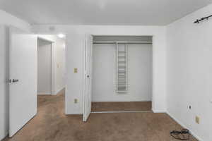 Unfurnished bedroom featuring dark carpet and a closet