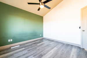 Unfurnished room featuring hardwood / wood-style flooring, ceiling fan, and lofted ceiling