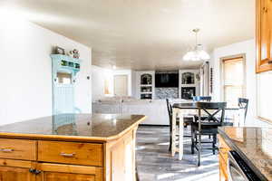 Kitchen with pendant lighting, a notable chandelier, dark wood-type flooring, and dishwasher