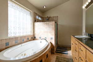 Bathroom featuring lofted ceiling, vanity, tile patterned floors, and separate shower and tub