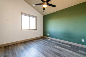 Empty room featuring hardwood / wood-style flooring, ceiling fan, and vaulted ceiling