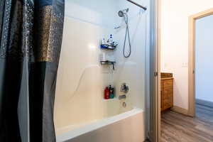 Bathroom with vanity, shower / tub combo, and hardwood / wood-style floors