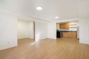 Kitchen featuring dark countertops, stainless steel electric range, light wood-style floors, and freestanding refrigerator